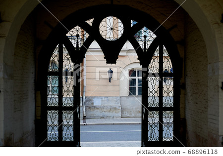 The forged semi-circular gate. Silhouette, overlooking the old street.Historic walks. The forged semi-circular gate. Silhouette, overlooking the old street.Historic walks. 68896118