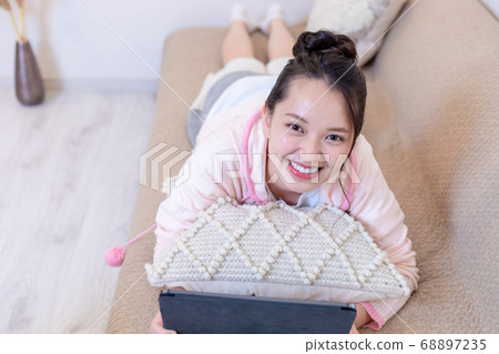 Woman lying on the sofa and looking at the tablet Woman lying on the sofa and looking at the tablet 68897235
