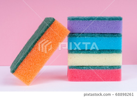 Multicolored sponges for washing dishes on top of each other on a pink background. Cleaning concept. Multicolored sponges for washing dishes on top of each other on a pink background. Cleaning concept. 68898261