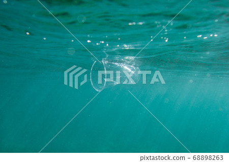 Plastic cup floats underwater in the open ocean. Environmental pollution concept. Plastic cup floats underwater in the open ocean. Environmental pollution concept. 68898263