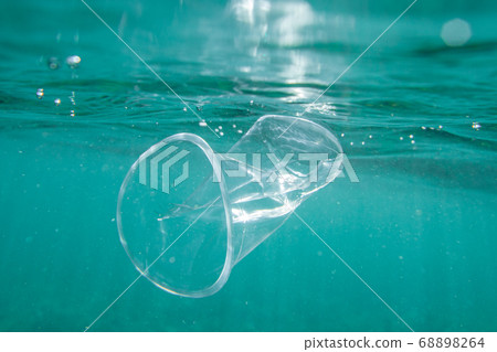 Plastic cup floats underwater in the open ocean. Environmental pollution concept. Plastic cup floats underwater in the open ocean. Environmental pollution concept. 68898264
