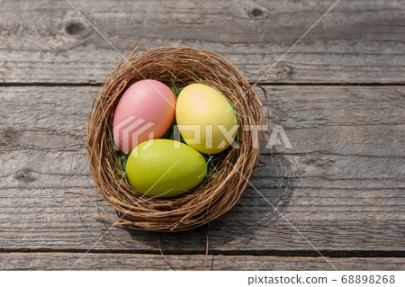 Multicolored easter eggs in a nest on a wooden background. Easter concept Multicolored easter eggs in a nest on a wooden background. Easter concept 68898268