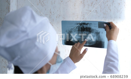 Closeup of dentist looking at dental x-ray plate. 68908239