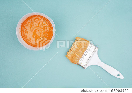 Paintbrush and bucket of ocher paint  68908953