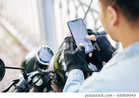 Motorcyclist checking map on smartphone Motorcyclist checking map on smartphone 68909049