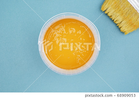 Bucket of ocher paint and paintbrush  68909053