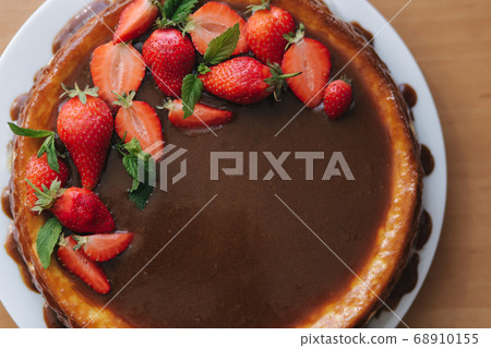 Tasty strawberry tart decorated with mint leaves on wooden table. Caramel glaze on top of tart. Vegan breakfast. Lactose and gluten free. Top view 68910155