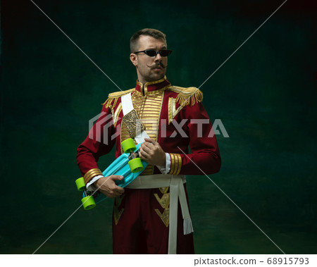 Young man as Nicholas II on dark green background. Retro style, comparison of eras concept. Young man as Nicholas II on dark green background. Retro style, comparison of eras concept. 68915793