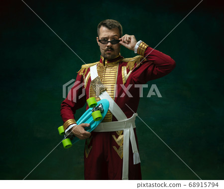 Young man as Nicholas II on dark green background. Retro style, comparison of eras concept. Young man as Nicholas II on dark green background. Retro style, comparison of eras concept. 68915794
