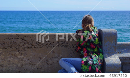 Woman looking at the sea from the bench 68917230