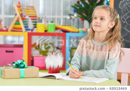 Cute girl sitting at table with gift Cute girl sitting at table with gift 68918469
