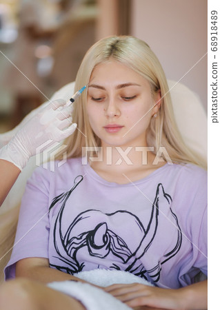 Hands of cosmetologist making injection in face, lips. Young woman gets beauty facial injections in medical clinic 68918489