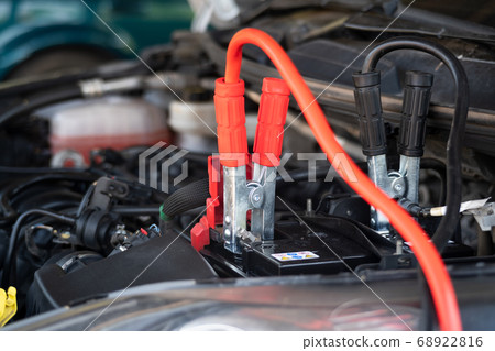 Using jumper cables to start-up a car engine. 68922816