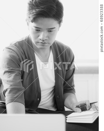 Young asian man writing in notebook. Young asian man writing in notebook. 68923388