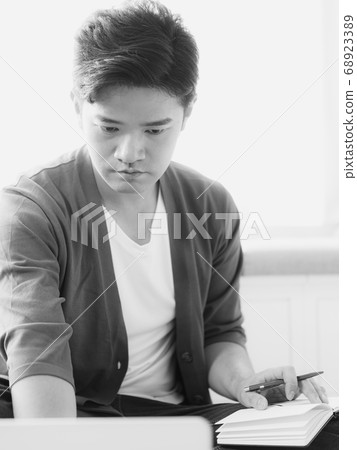 Young asian man writing in notebook. Young asian man writing in notebook. 68923389