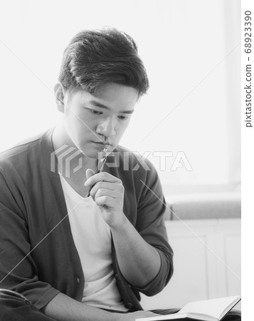 Young asian man writing in notebook. Young asian man writing in notebook. 68923390