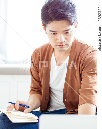 Young asian man writing in notebook. Young asian man writing in notebook. 68923394