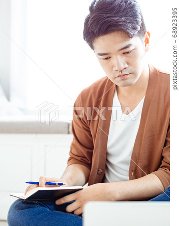 Young asian man writing in notebook. Young asian man writing in notebook. 68923395