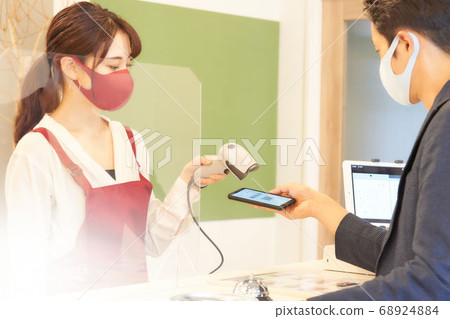 A female clerk in a mask reading a barcode 68924884