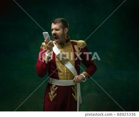 Young man as Nicholas II on dark green background. Retro style, comparison of eras concept. Young man as Nicholas II on dark green background. Retro style, comparison of eras concept. 68925336