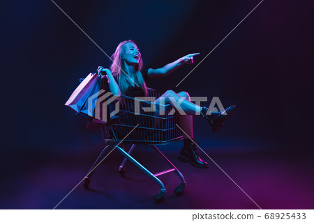 Portrait of young woman in neon light on dark backgound. The human emotions, black friday, cyber monday, purchases, sales, finance concept. 68925433