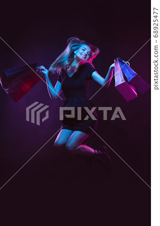 Portrait of young woman in neon light on dark backgound. The human emotions, black friday, cyber monday, purchases, sales, finance concept. 68925477