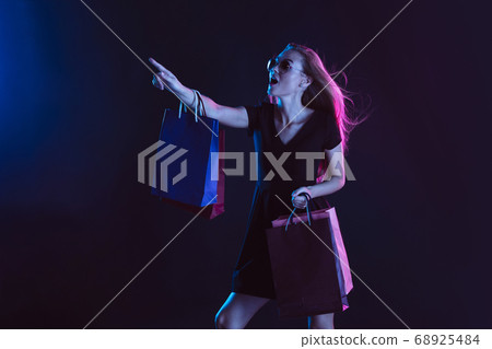 Portrait of young woman in neon light on dark backgound. The human emotions, black friday, cyber monday, purchases, sales, finance concept. 68925484