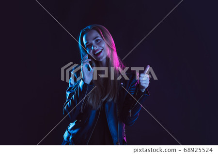 Portrait of young woman in neon light on dark backgound. The human emotions, black friday, cyber monday, purchases, sales, finance concept. Portrait of young woman in neon light on dark backgound. The human emotions, black friday, cyber monday, purchases, sales, finance concept. 68925524