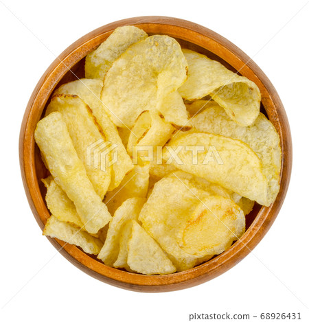 Salted potato chips with peel, also crisps, in wooden bowl. Thin slices of potato, deep fried in oil until crunchy. Served as snack, side dish or appetizer. Close-up from above over white, food photo. Salted potato chips with peel, also crisps, in wooden bowl. Thin slices of potato, deep fried in oil until crunchy. Served as snack, side dish or appetizer. Close-up from above over white, food photo. 68926431