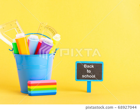 A metal bucket with highlighter marker pen and school ruler on a blue background. A metal bucket with highlighter marker pen and school ruler on a blue background. 68927044