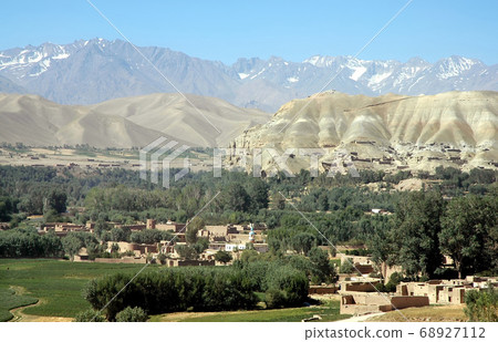 Bamyan (Bamiyan) in Central Afghanistan. A view over the Bamyan (Bamiyan) Valley showing the town, trees, fields and snow capped mountains. The town is home to the famous UNESCO Buddhas of Afghanistan Bamyan (Bamiyan) in Central Afghanistan. A view over the Bamyan (Bamiyan) Valley showing the town, trees, fields and snow capped mountains. The town is home to the famous UNESCO Buddhas of Afghanistan 68927112