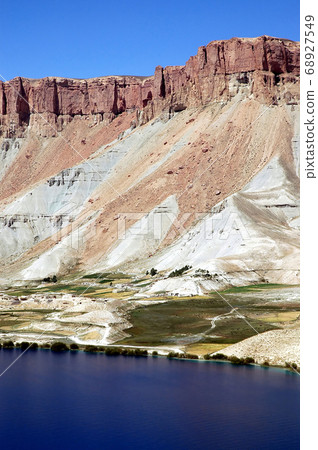 Band-e Amir lakes near Bamyan (Bamiyan) in Central Afghanistan. Band e Amir was the first national park in Afghanistan. A natural blue lake at Band e Amir with the red Hindu Kush mountains behind. Band-e Amir lakes near Bamyan (Bamiyan) in Central Afghanistan. Band e Amir was the first national park in Afghanistan. A natural blue lake at Band e Amir with the red Hindu Kush mountains behind. 68927549
