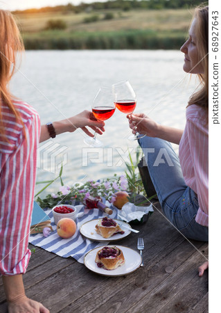 two girls enjoying picnic on a wooden pier two girls enjoying picnic on a wooden pier 68927643