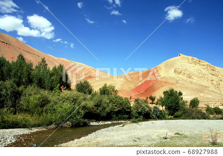 Mountain scenery of Afghanistan near Yakawlang in Bamyan (Bamiyan) Province. These colorful mountains are at the western end of the Hindu Kush mountain range in Central Afghanistan. River and trees. Mountain scenery of Afghanistan near Yakawlang in Bamyan (Bamiyan) Province. These colorful mountains are at the western end of the Hindu Kush mountain range in Central Afghanistan. River and trees. 68927988