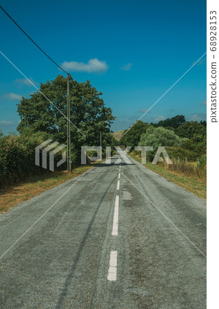 Deserted road passing through rural landscape 68928153