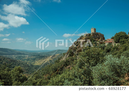 Hilly landscape with tower of castle over rocky cliff 68928177