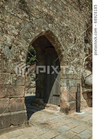 Open gateway with wooden door on a stone wall Open gateway with wooden door on a stone wall 68928185