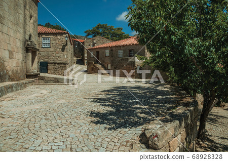 Houses made of stone with tree and deserted alley 68928328