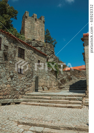 Houses made of stone with alley on slope and tower 68928332
