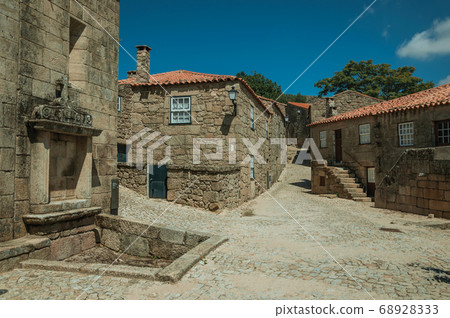 Houses made of stone with tree and deserted alley Houses made of stone with tree and deserted alley 68928333