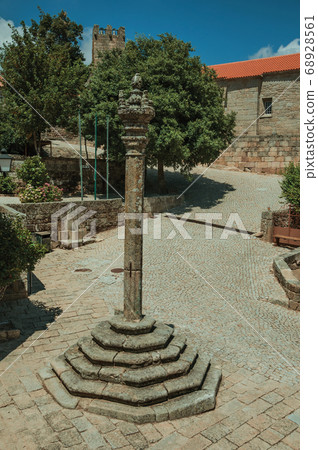 Stone pillory in square encircled by gothic houses 68928561