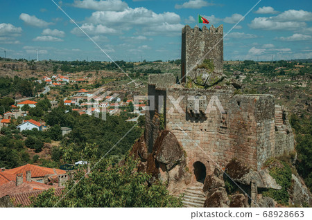 Stone castle and tower over rocky cliff 68928663