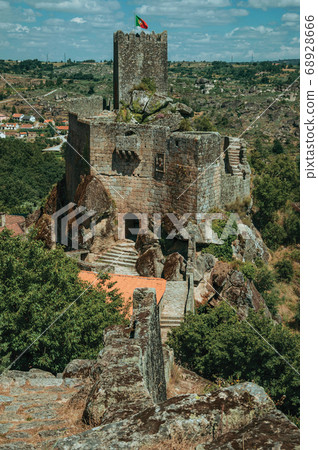 Stone castle and tower over rocky cliff 68928666