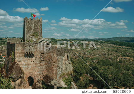 Stone castle and tower over rocky cliff 68928669
