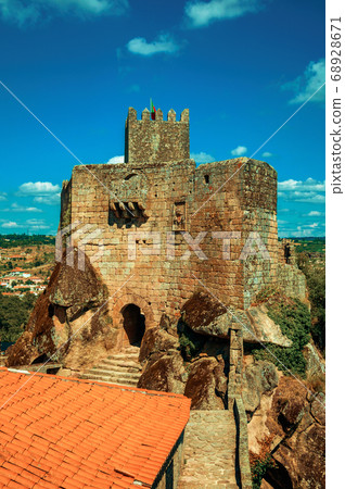Stone castle and tower over rocky cliff 68928671