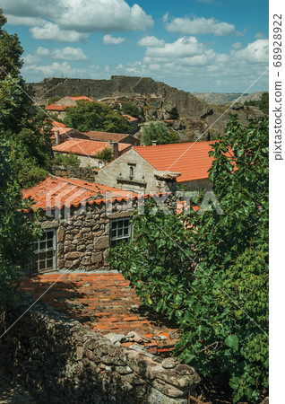 Roofs of stone old houses with leafy treetops 68928922