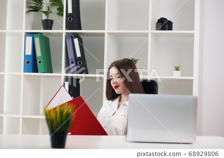 Business woman sitting at a desk with a laptop and looking away in the office 68929806