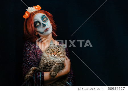 A young woman in day of the dead mask skull face art. A young woman in day of the dead mask skull face art. 68934627