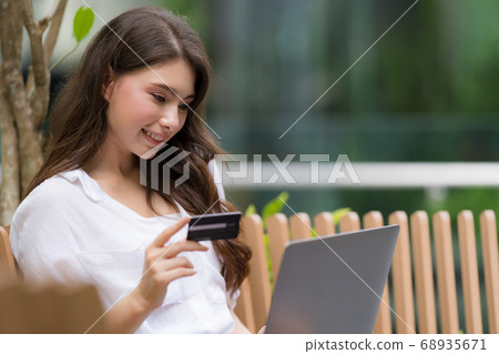 Young woman sitting with smiley face using laptop Young woman sitting with smiley face using laptop 68935671