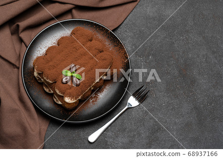 Classic tiramisu dessert on ceramic plate on concrete background Classic tiramisu dessert on ceramic plate on concrete background 68937166